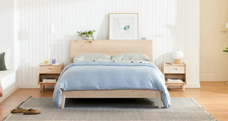 Ash Rise bed frame with a headboard and blue linen in a staged bedroom.